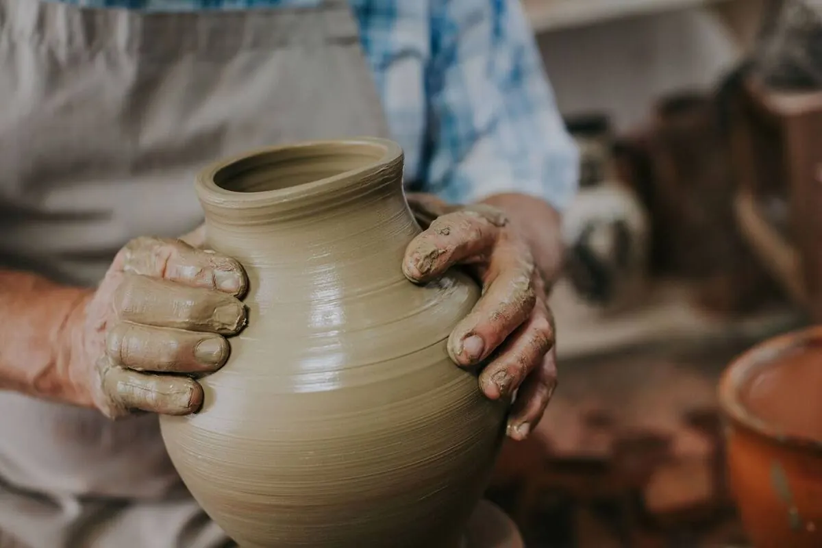 Potter's clay-covered hands shaping a vase on the wheel in the Dizayn74 studio in Kyrenia